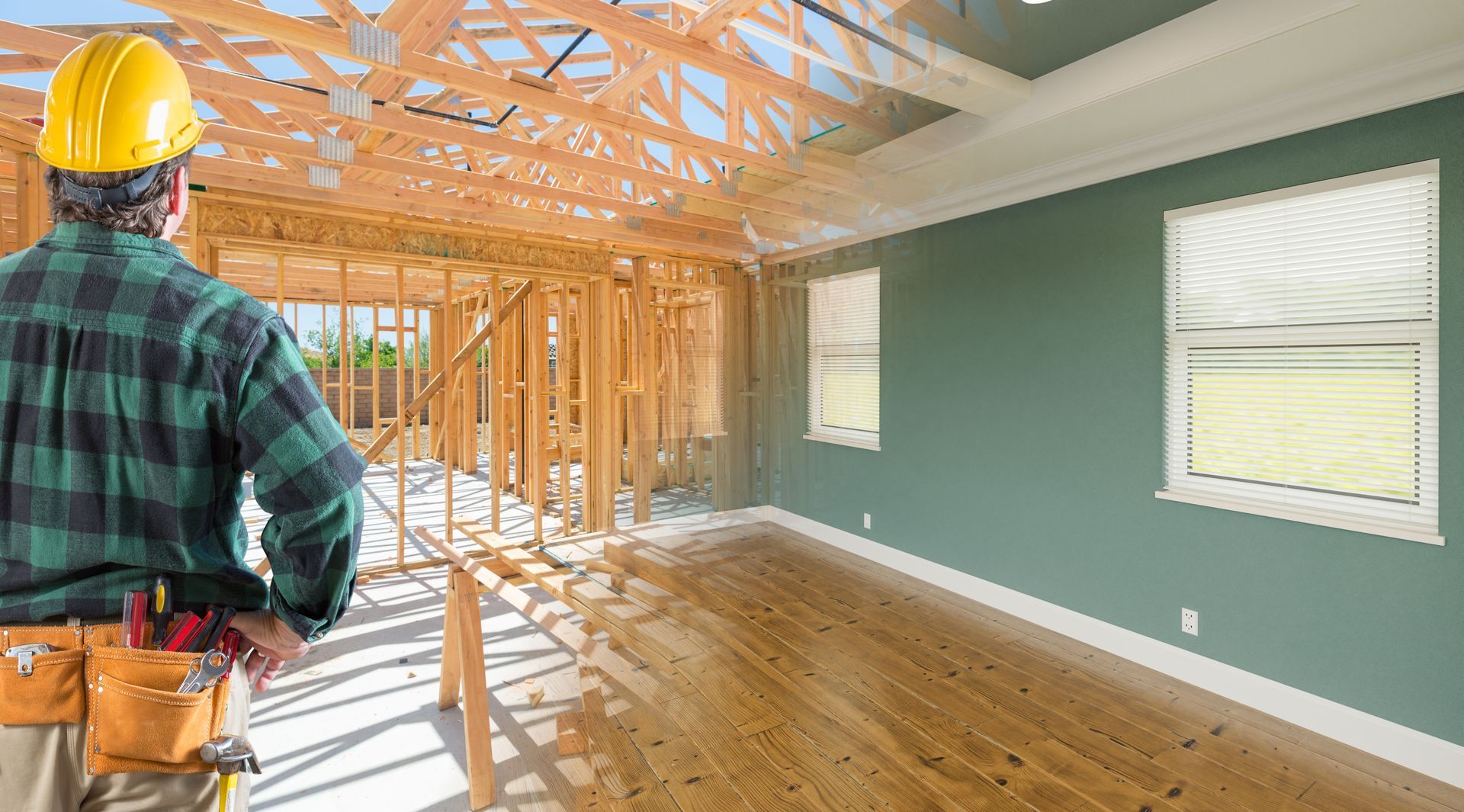 A man wearing a hard hat is standing in a room under construction.