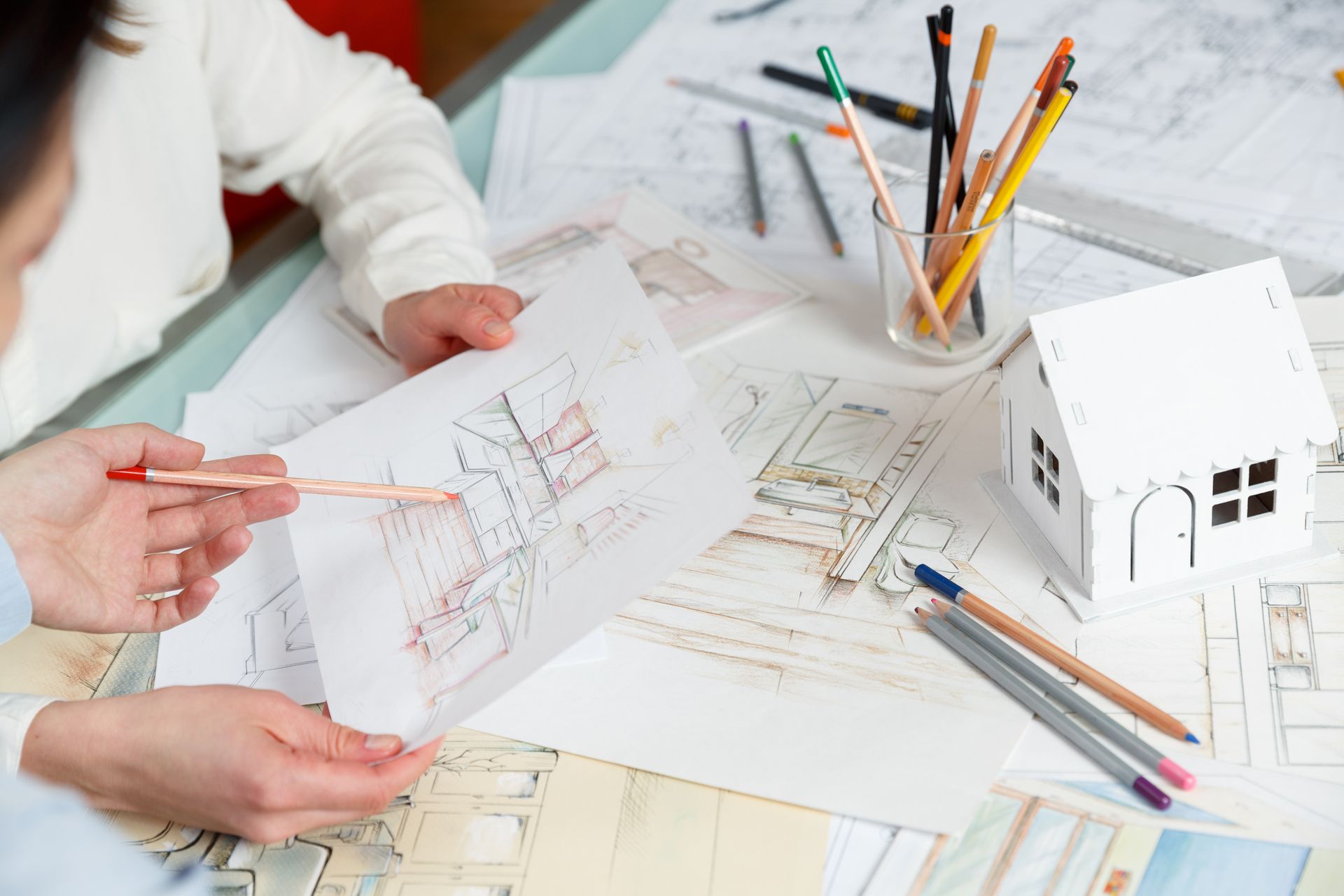 A couple of people are sitting at a table looking at a drawing of a house.