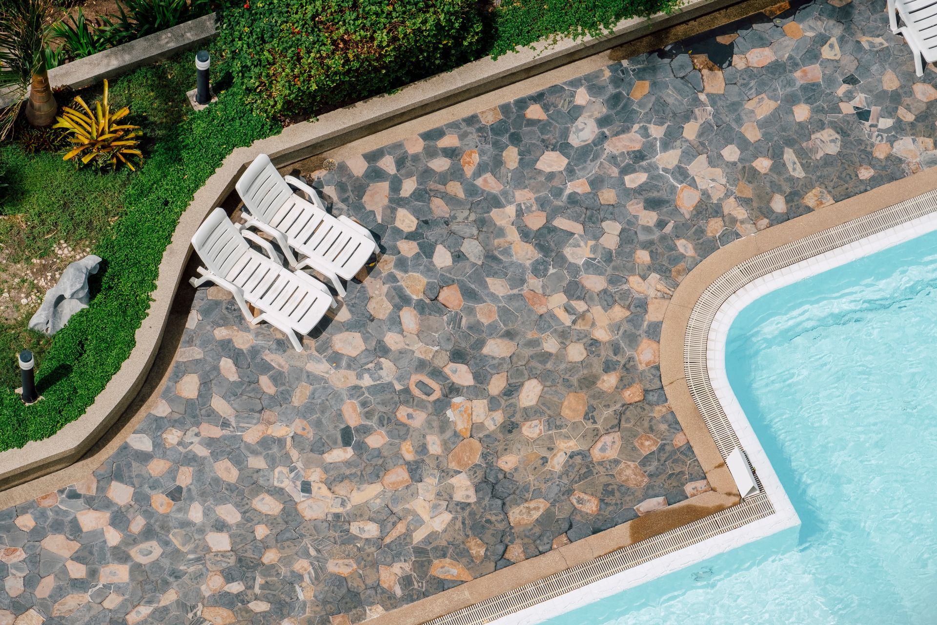 An aerial view of a swimming pool with two lounge chairs next to it.