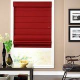 A living room with a red roman shade on a window.