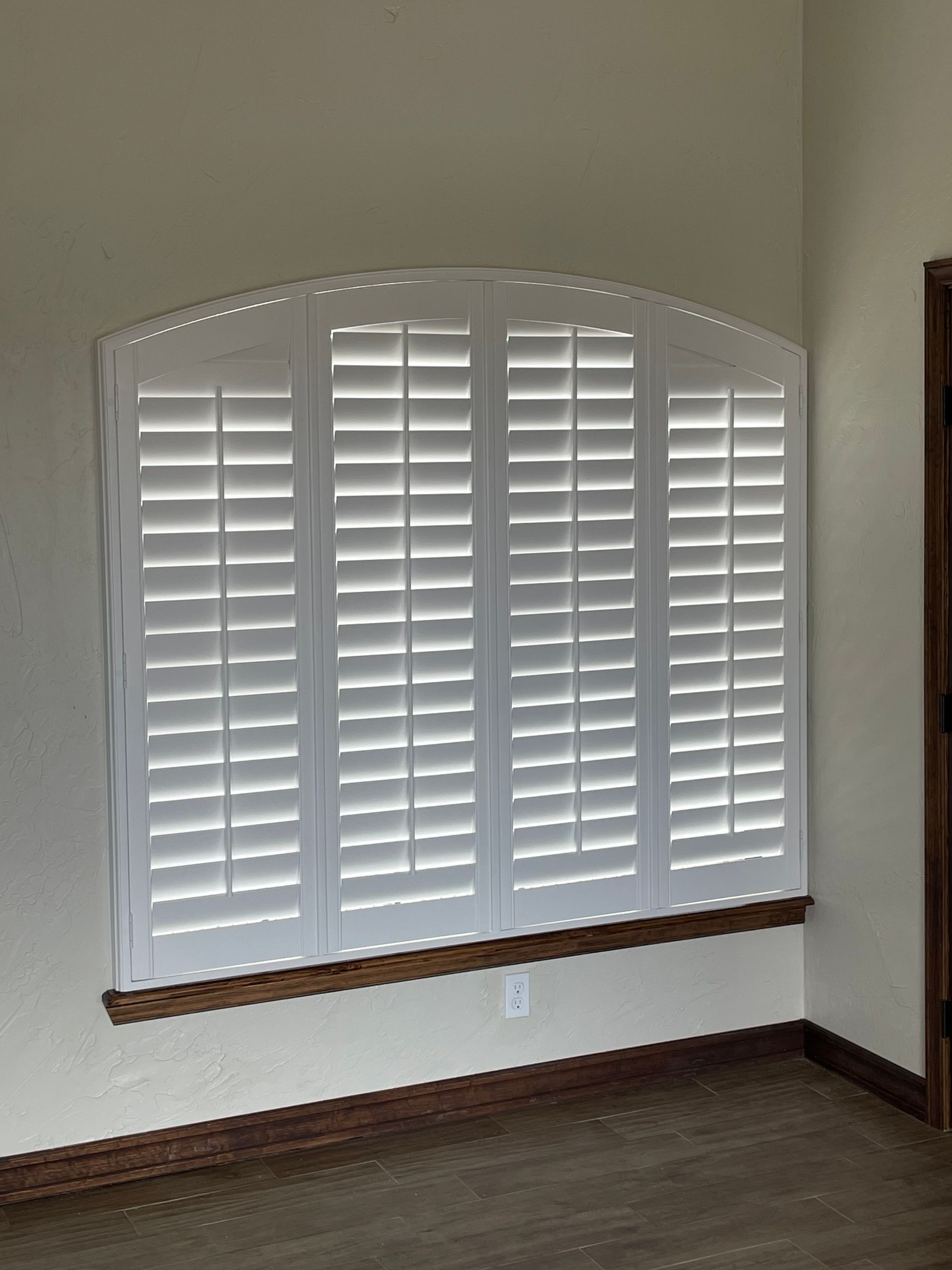 A room with a window with white shutters on it