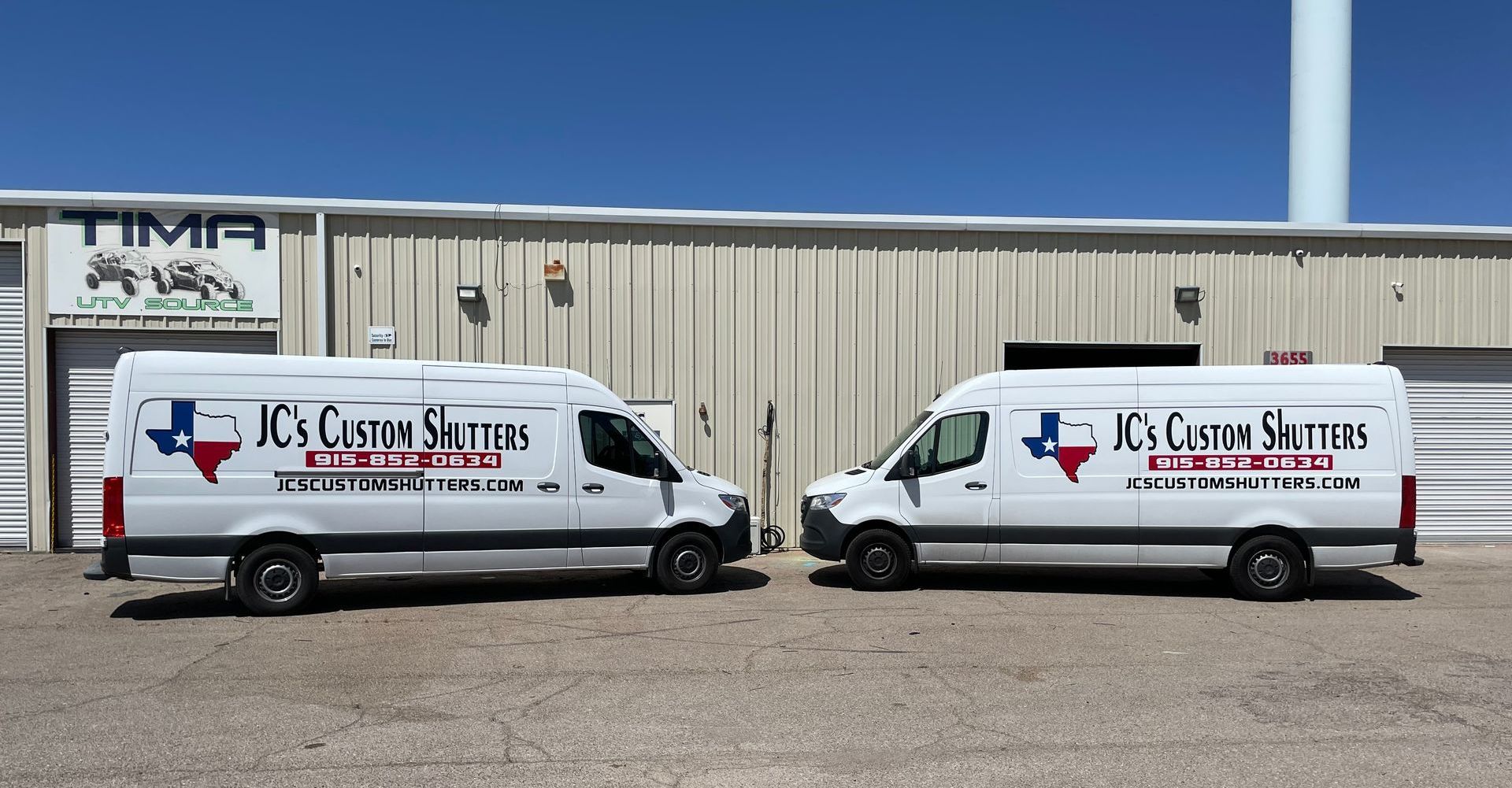 Two white vans are parked in front of a building that says tima