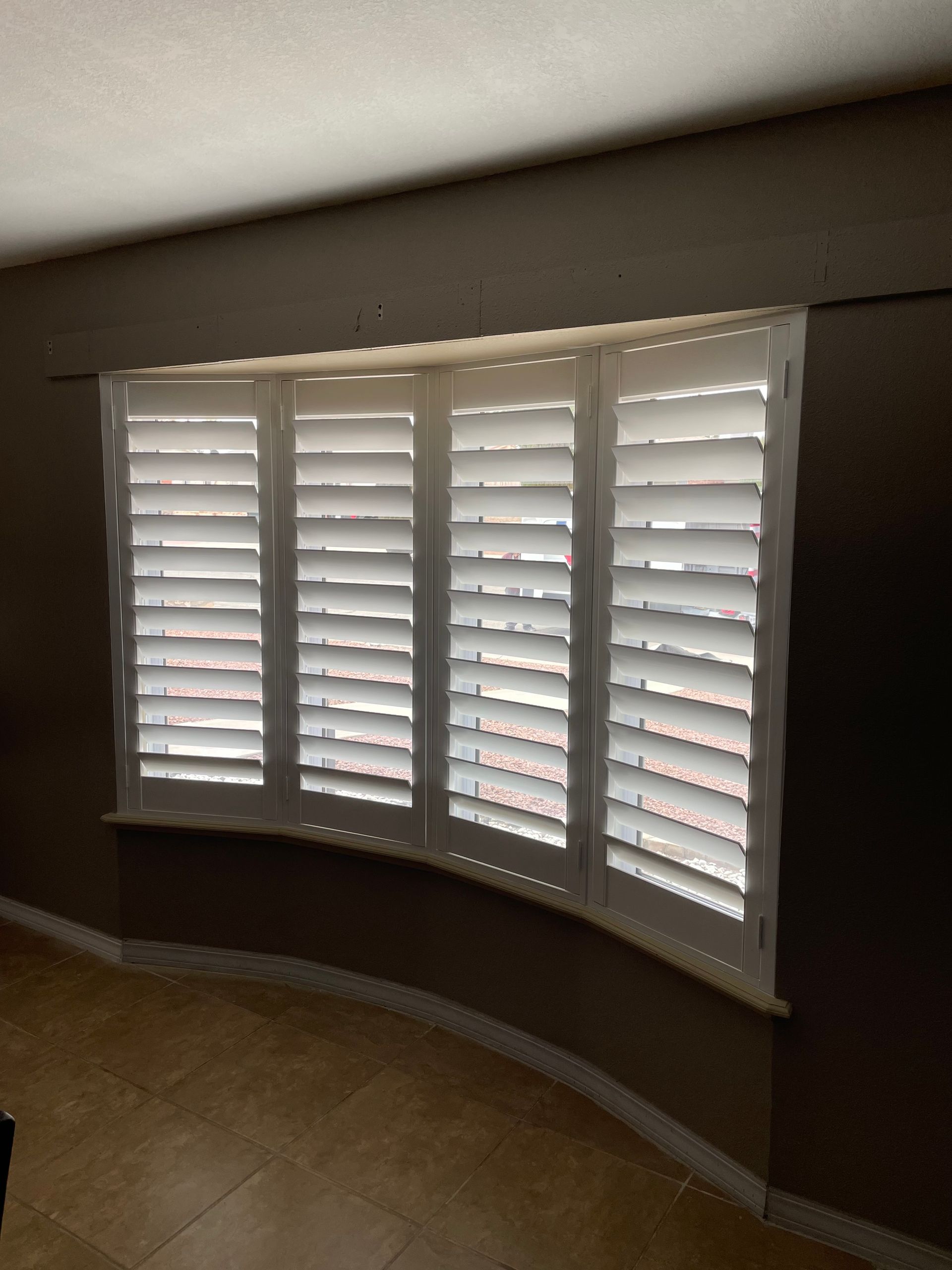 A curved window with white shutters on it