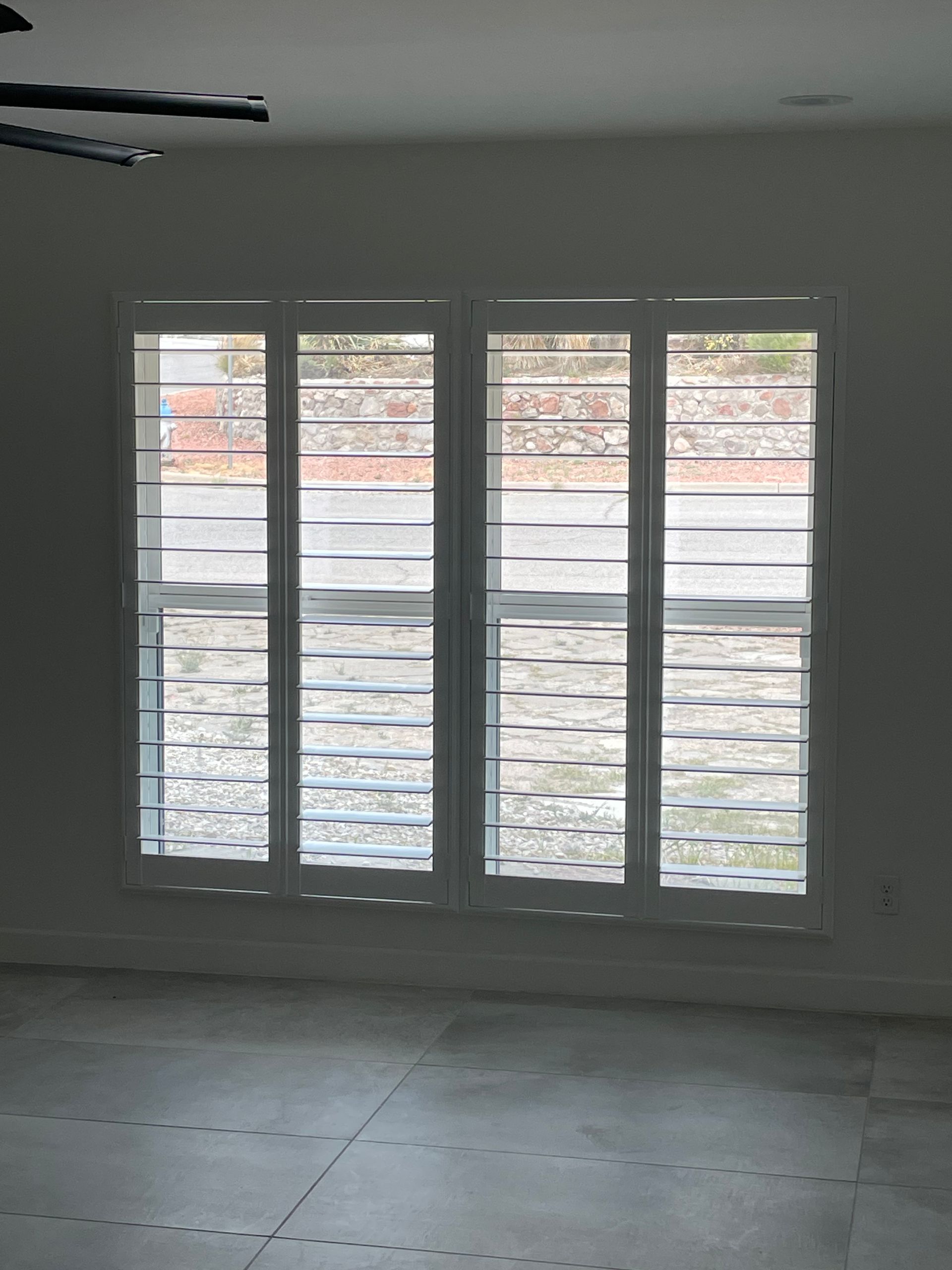 A room with two windows and a ceiling fan.