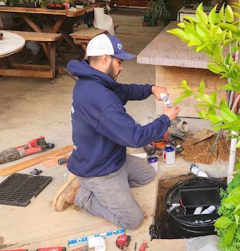 A Venture Plumbing technician kneeling down performing plumbing service
