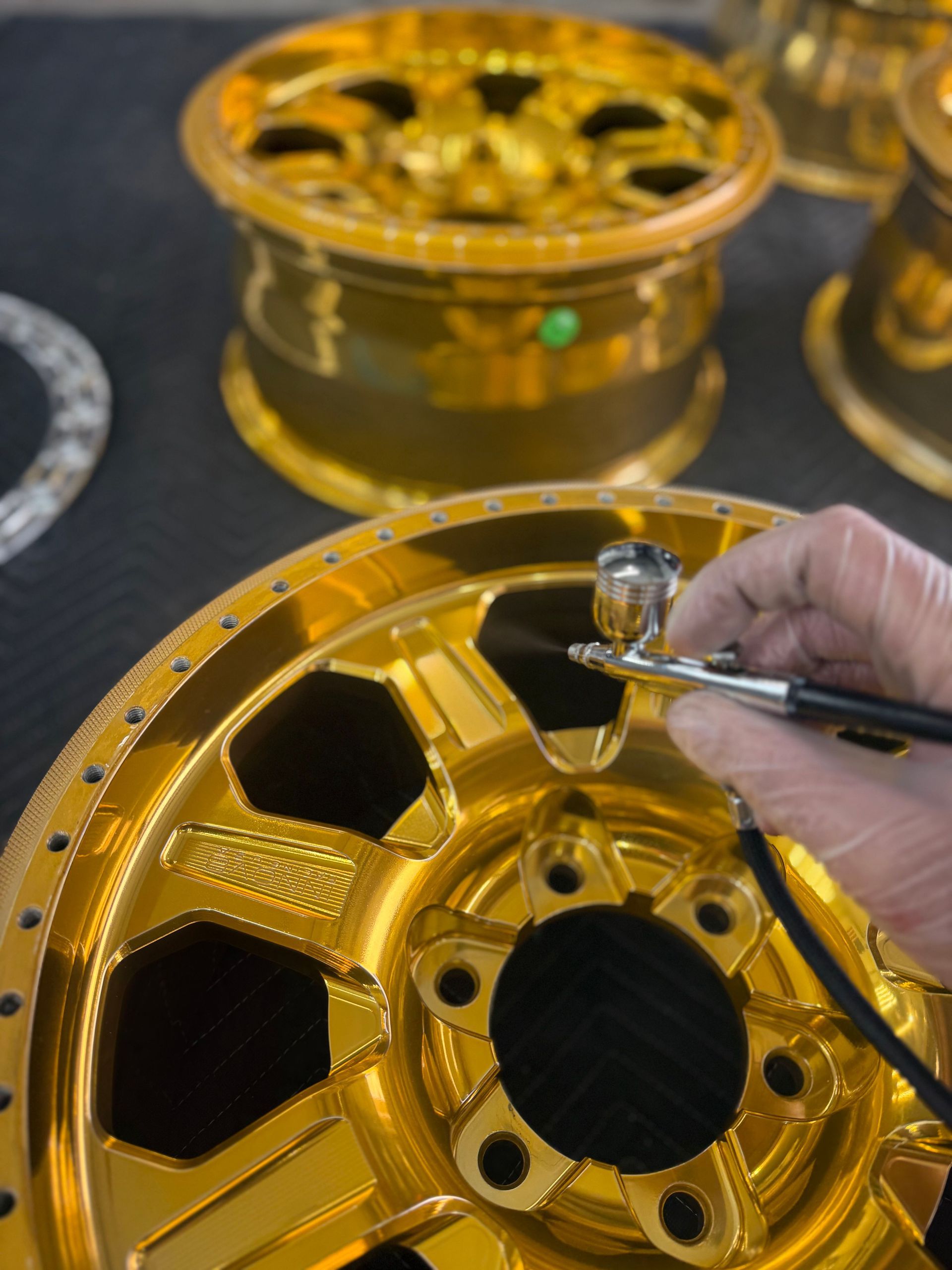 A person is spray painting a wheel with an airbrush