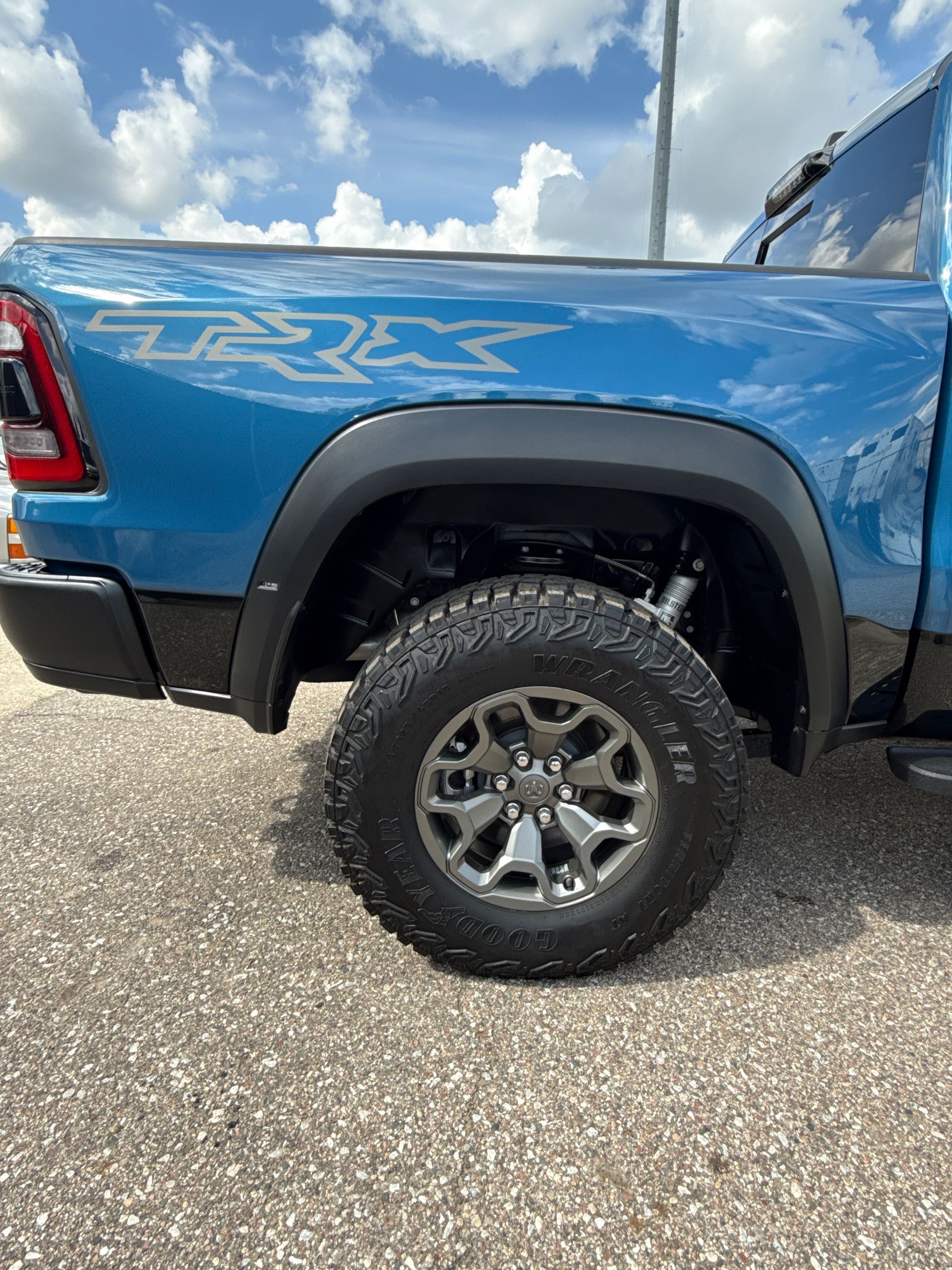 A blue ram truck is parked on a gravel road.