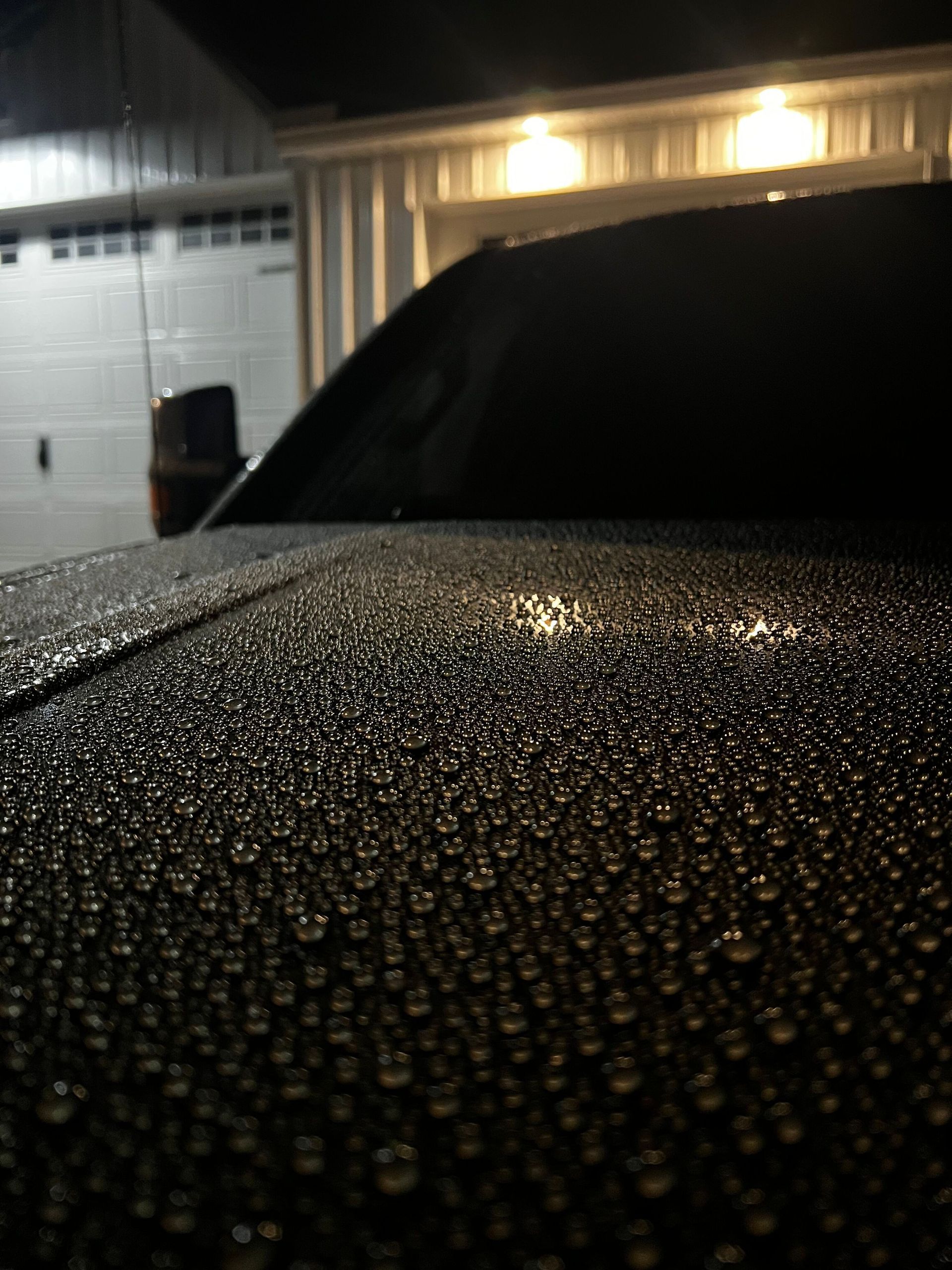 A close up of a car hood with water drops on it