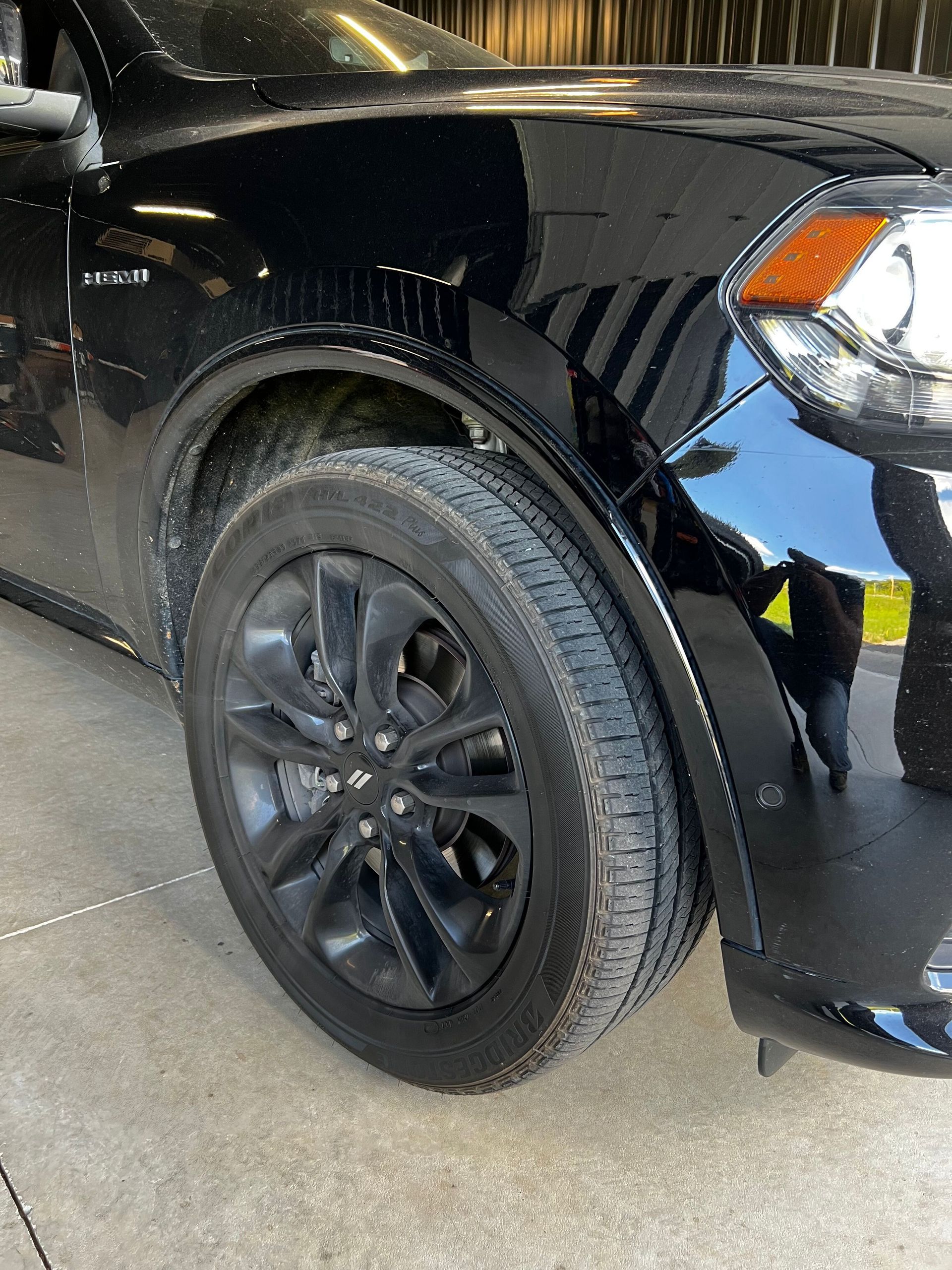 A black car with black wheels and tires is parked in a garage.