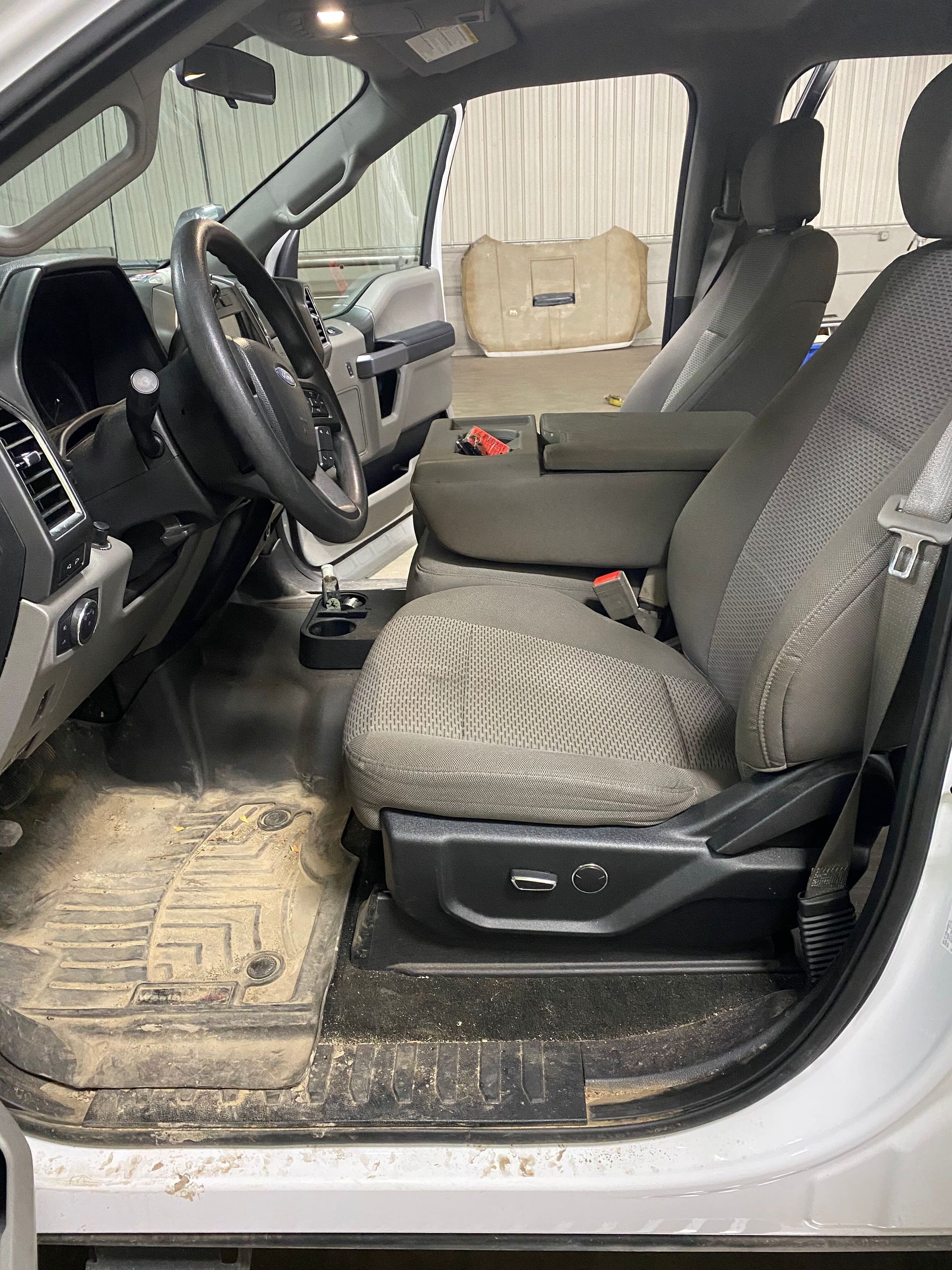 The interior of a white truck with the door open and dirty seats.