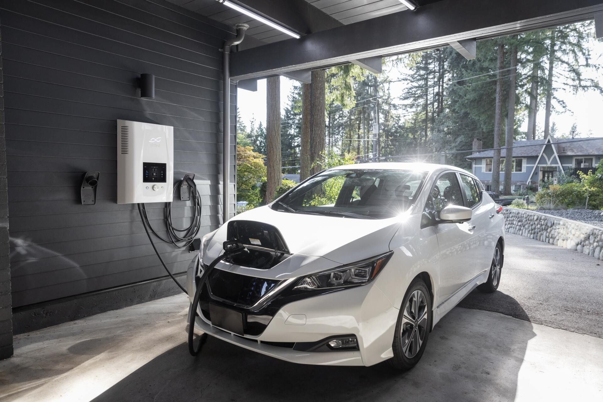 A white electric car is being charged in a garage.