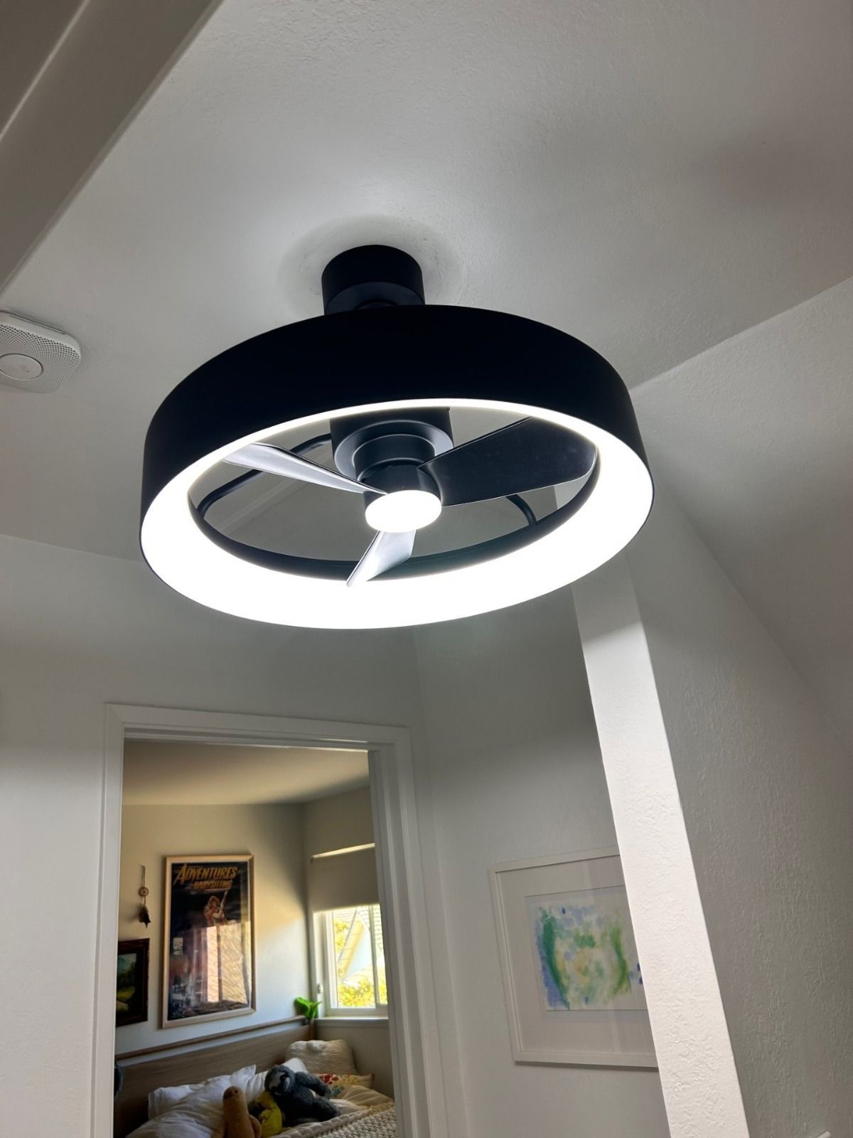 Modern black ceiling fan with a bright ring light in a white hallway