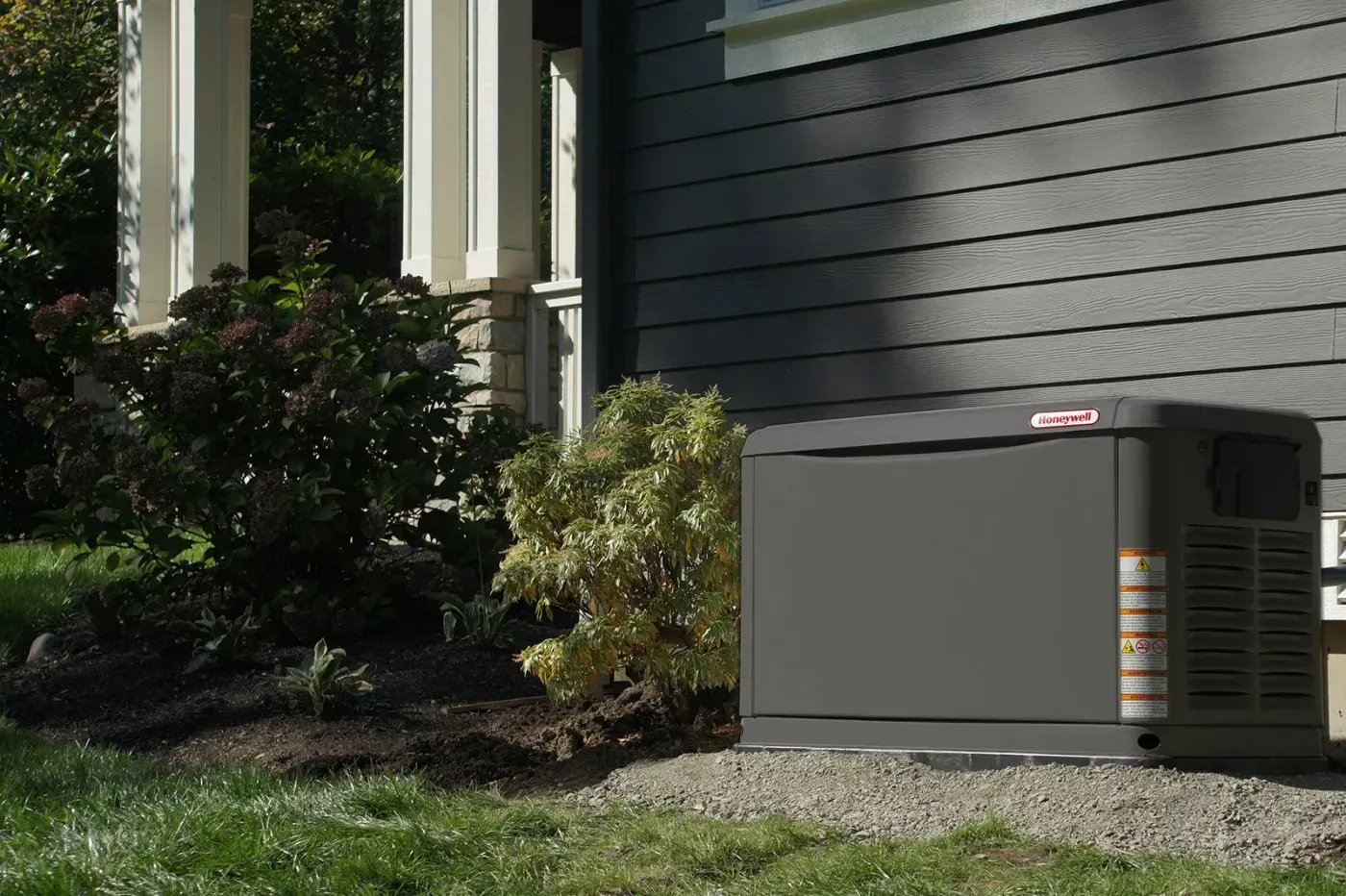 Gray Generac electrical control box mounted on an exterior wall with conduit pipes
