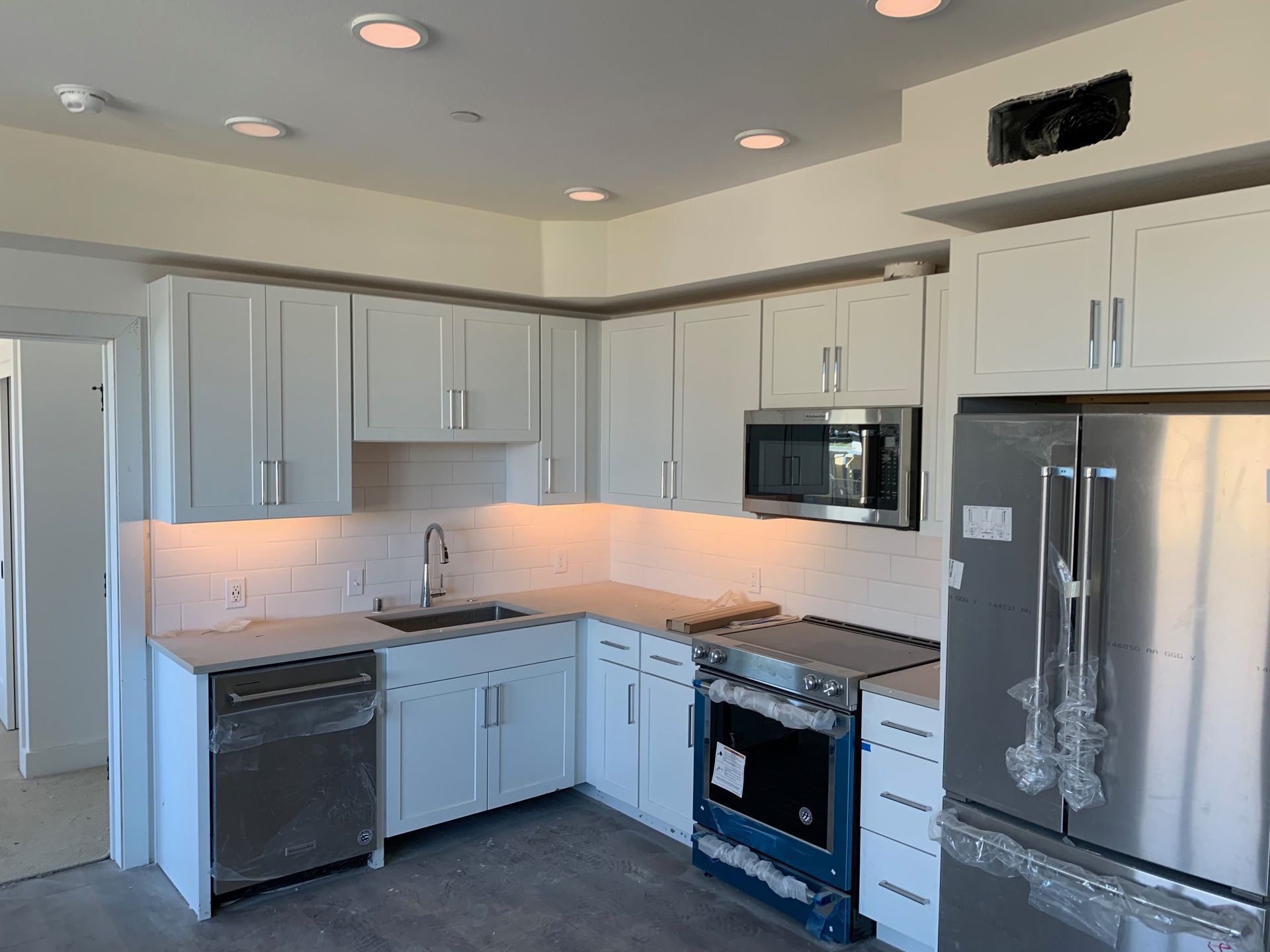 Modern kitchen with white cabinets, stainless steel appliances, and marble countertops