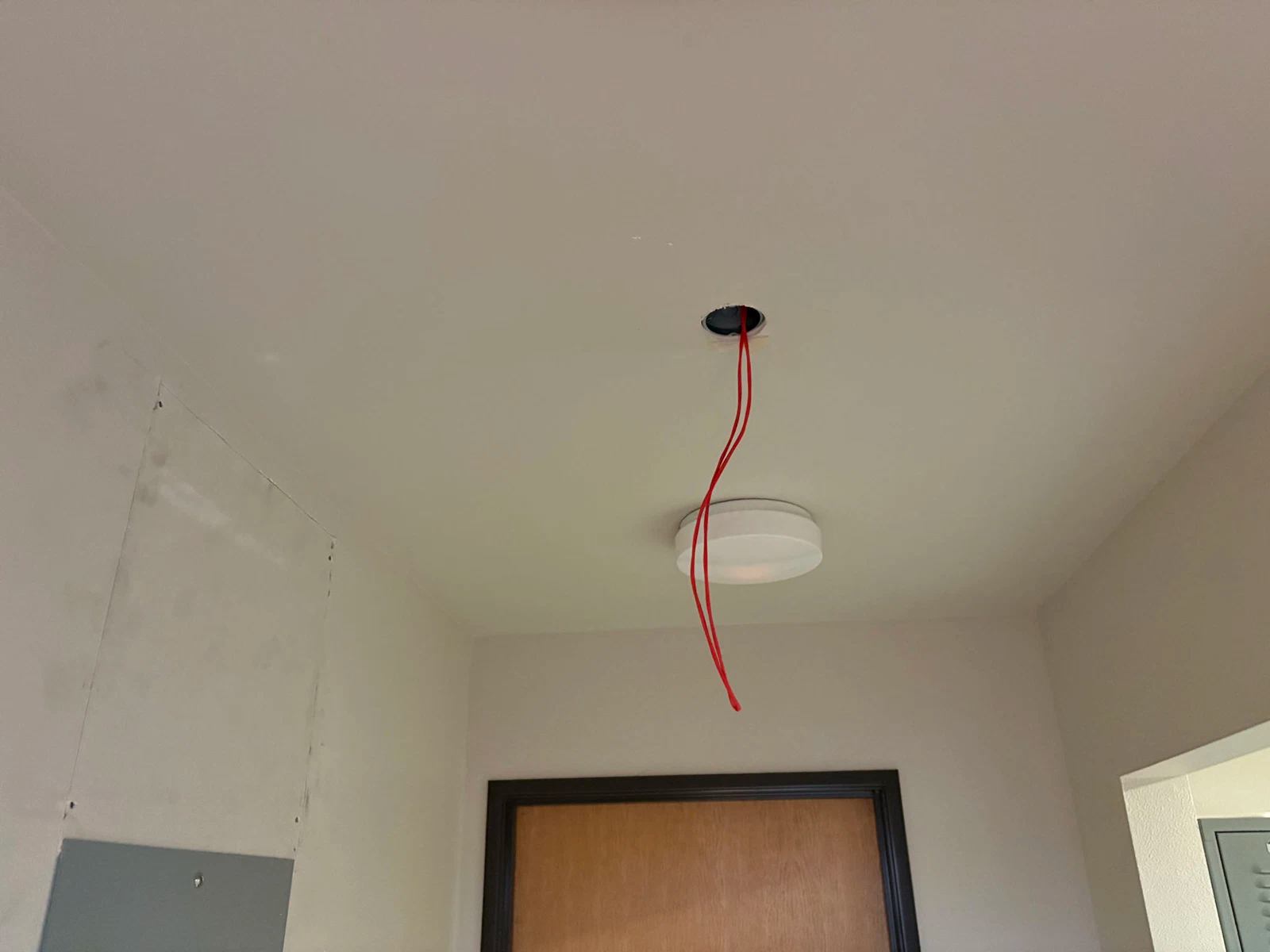 Ceiling with exposed red wires and a light fixture, possibly for electrical work.