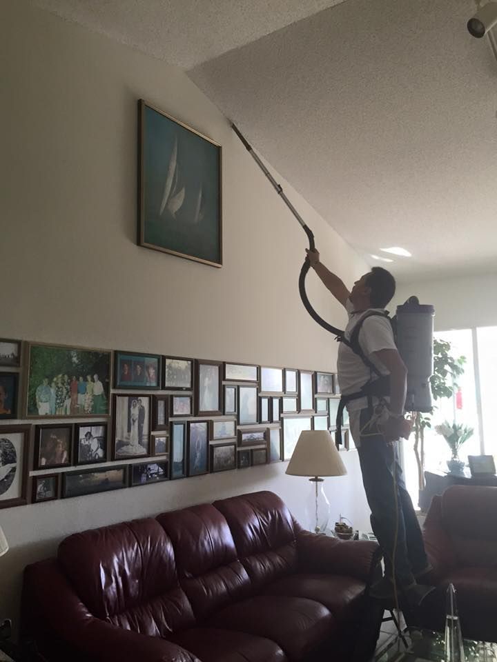 A man is spraying a ceiling in a living room