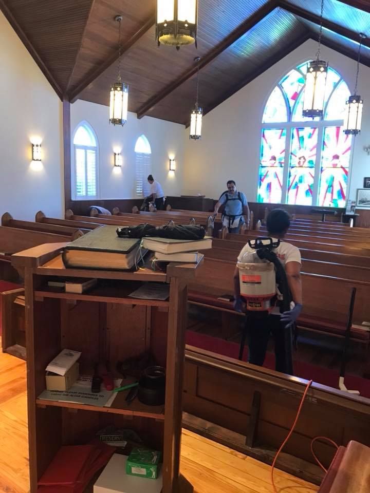 A woman is cleaning a church with a backpack.