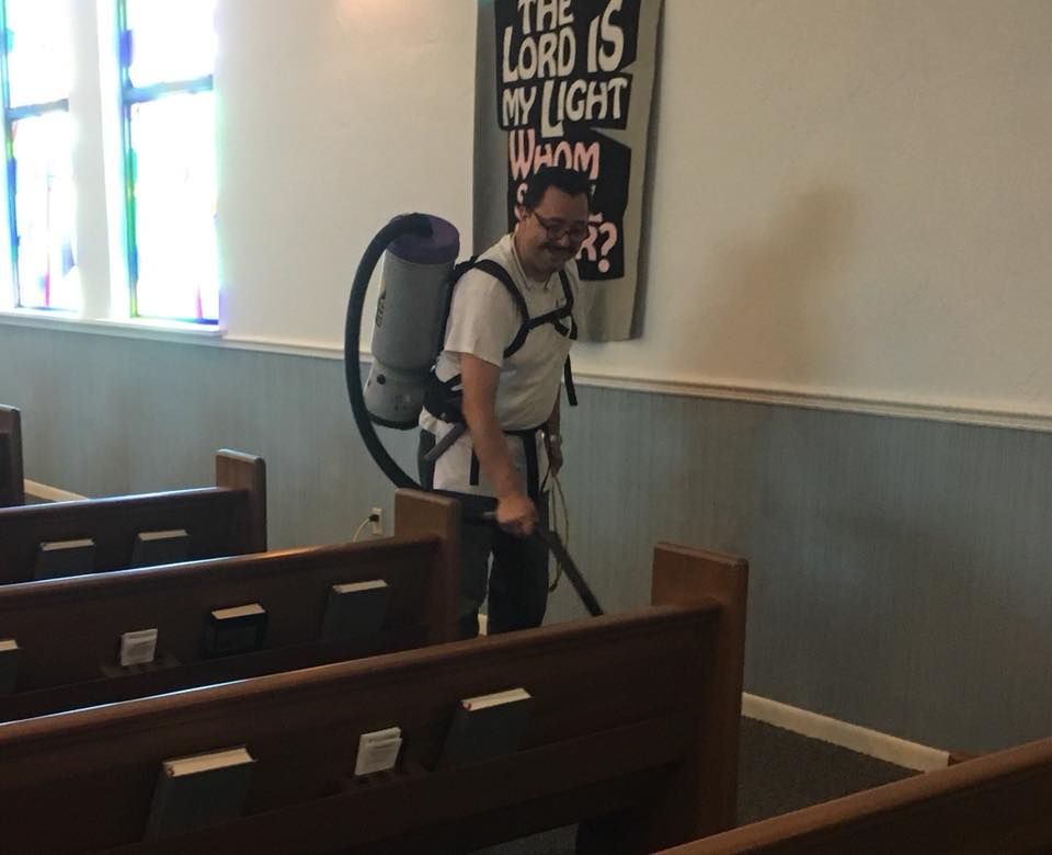 A man is cleaning a church with a vacuum cleaner.