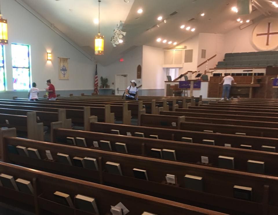 A church with rows of wooden benches and a cross on the wall