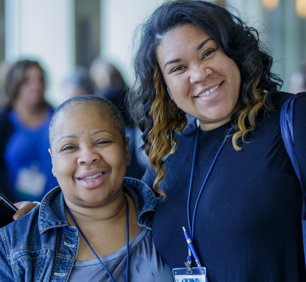 Two women are posing for a picture and one has a name tag that says ' a ' on it