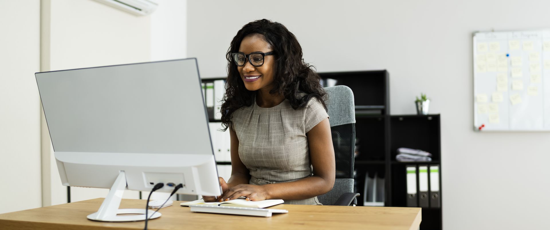 Person smiling at a desk using a computer in an office