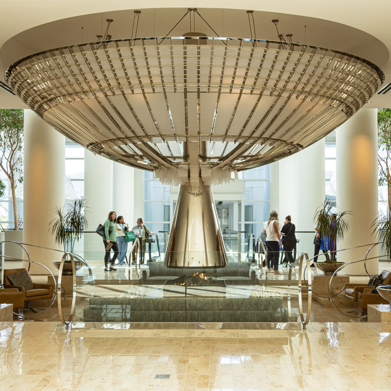 Grand lobby with large chandelier, people standing around a water feature.