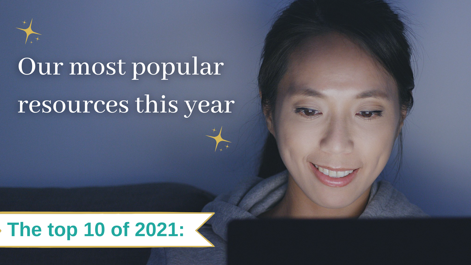 A woman is smiling while looking at a computer screen.
