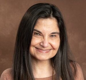 A woman with long black hair is smiling for the camera.