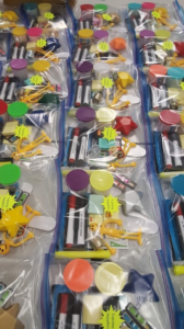 A bunch of plastic bags filled with toys are lined up on a table.