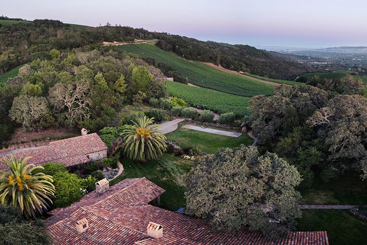 Rooftops overlooking green hills and a valley at dusk