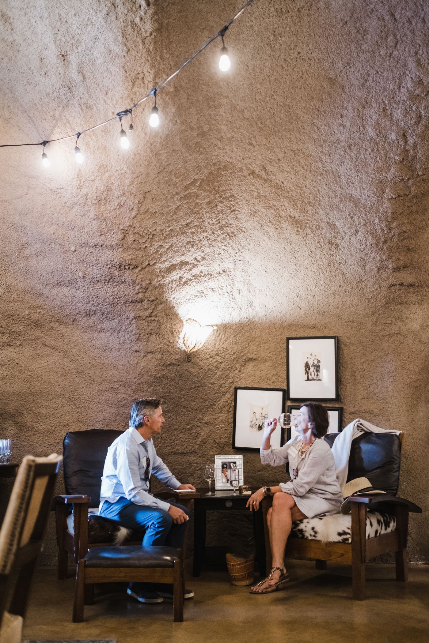 Two people seated in a cozy café with textured walls and framed art.