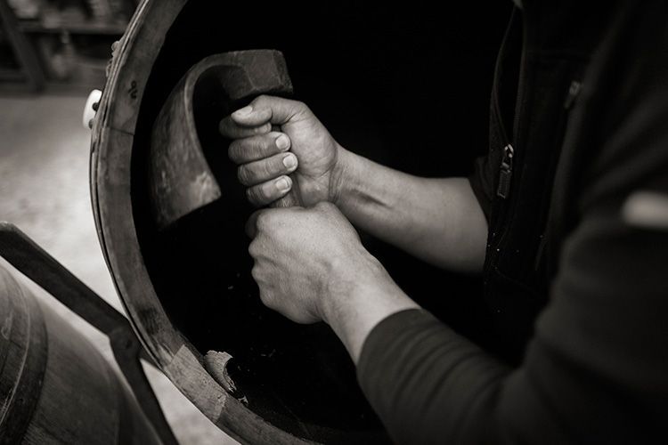 Hands gripping a large metal wheel or valve in a dark industrial setting.