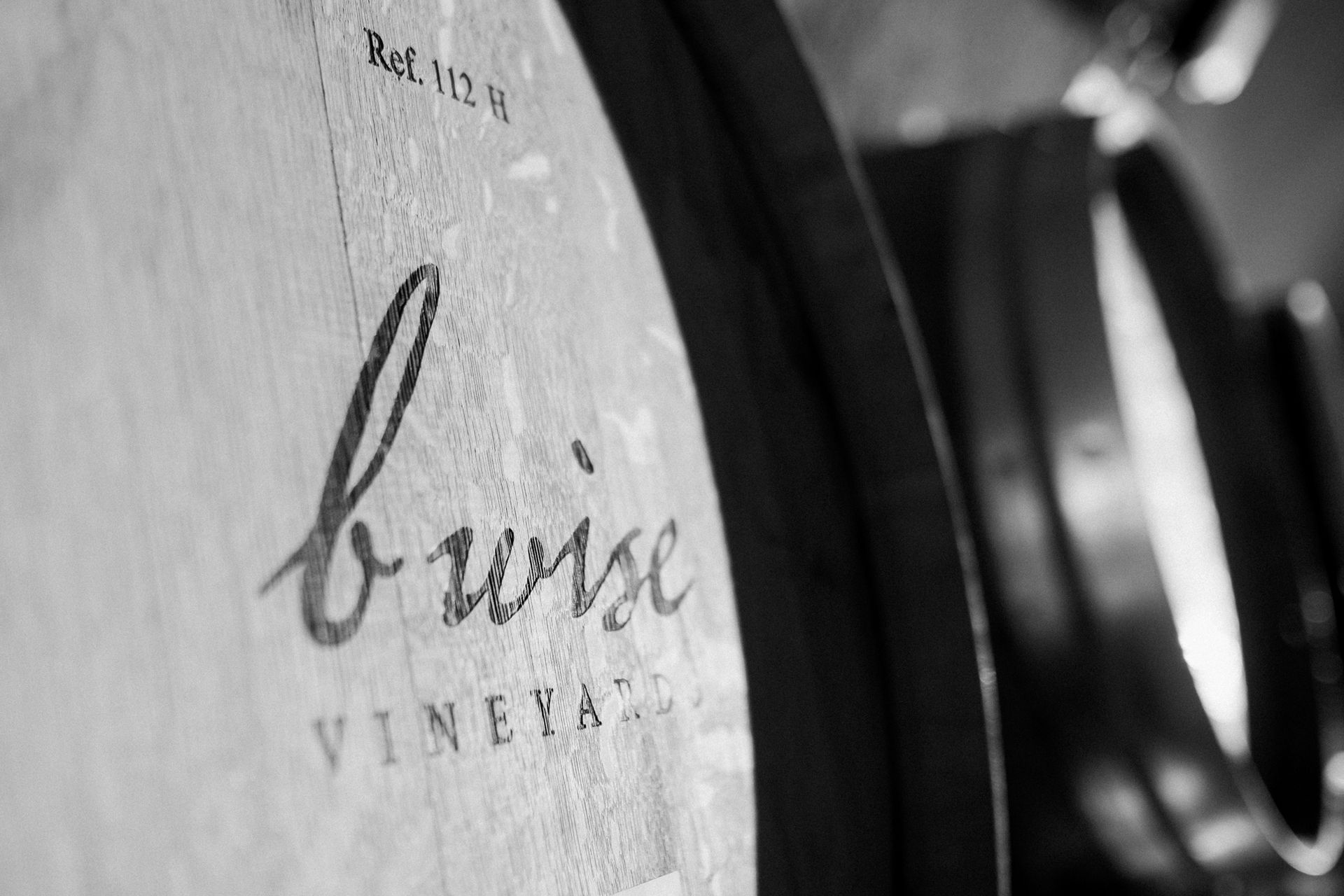 Close-up of a wine barrel labeled “buise VINEYARD” in a cellar