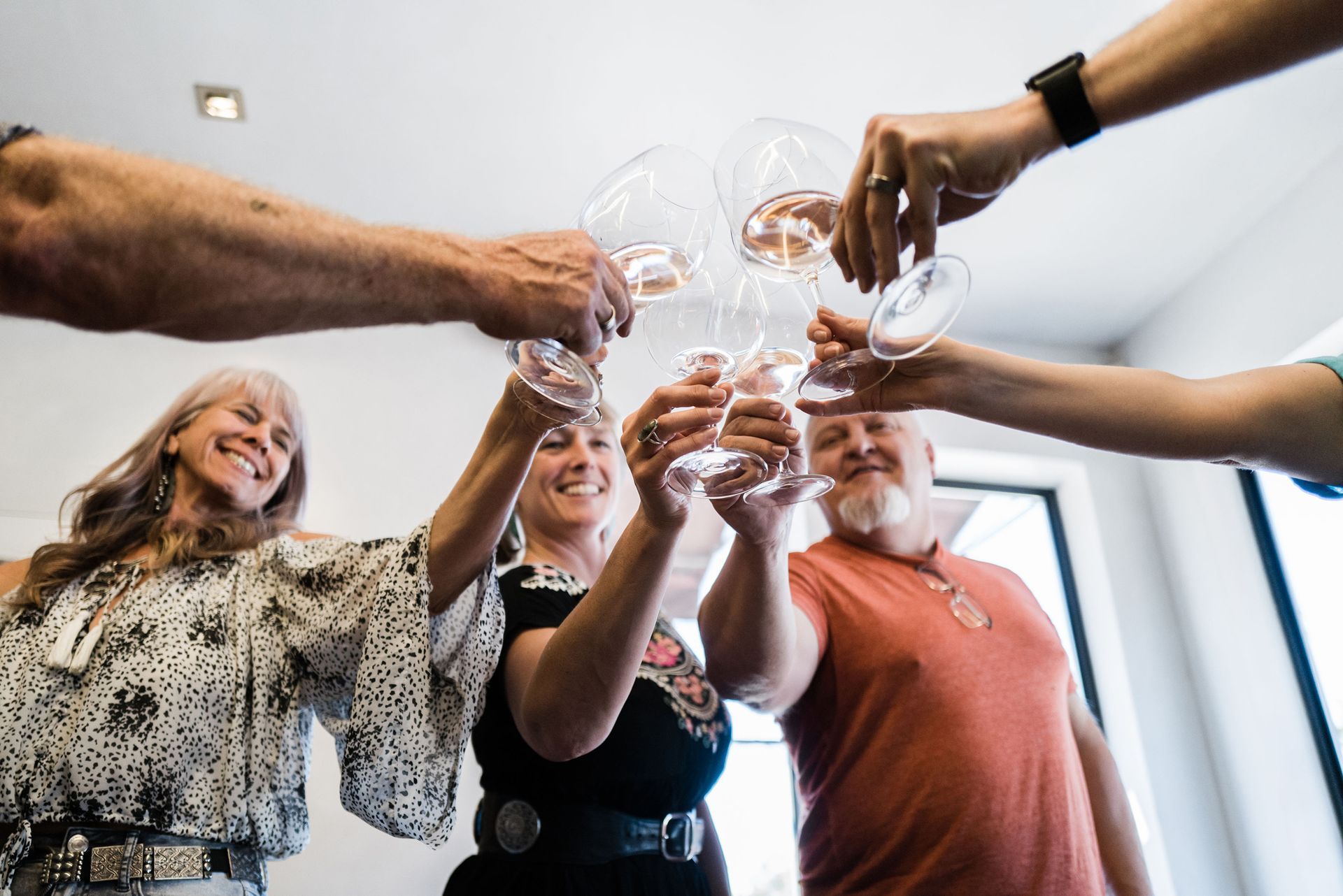 Group of people toasting with wine glasses in a bright office, smiling and celebrating.