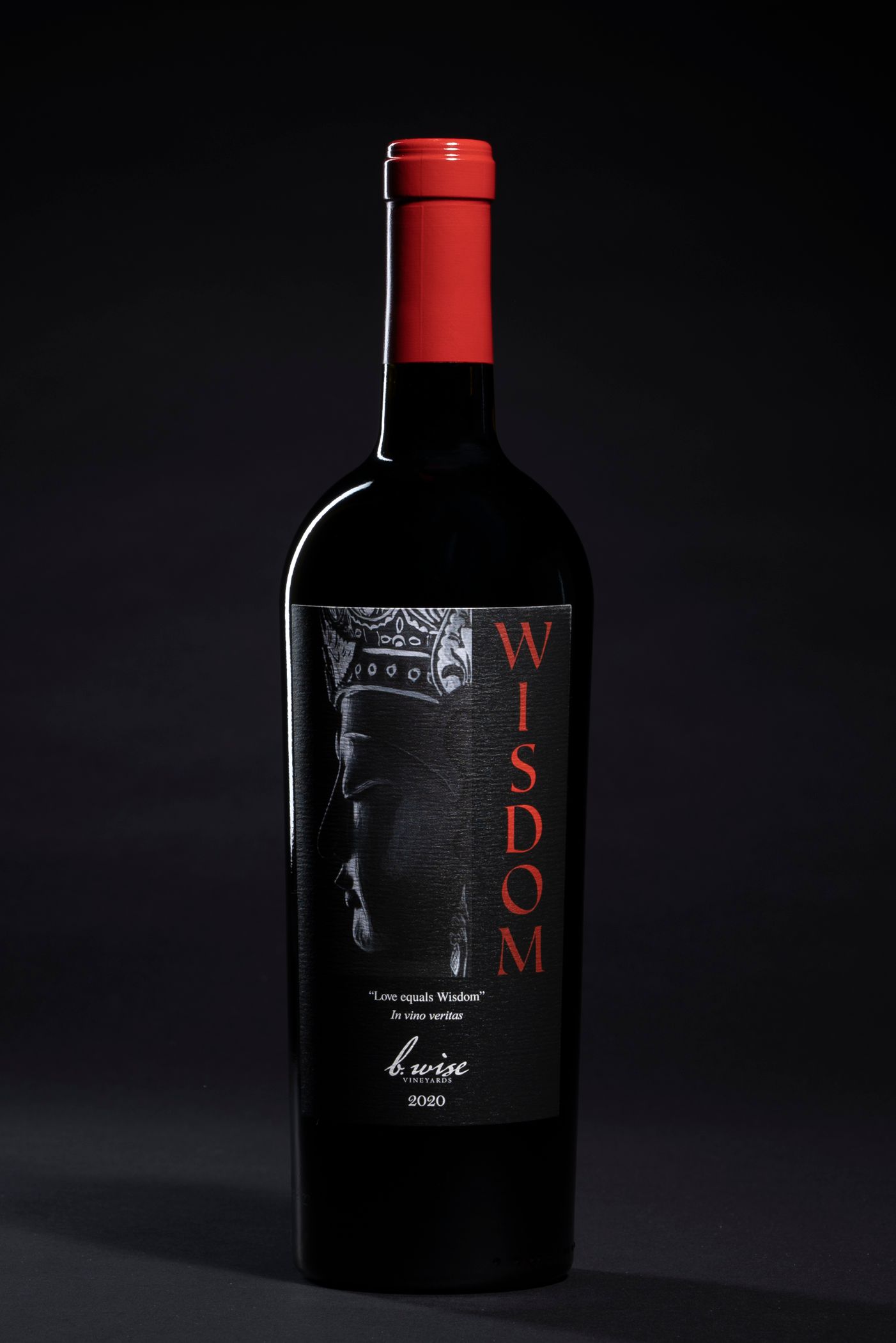 Black wine bottle with a red cap and red vertical label on a dark background