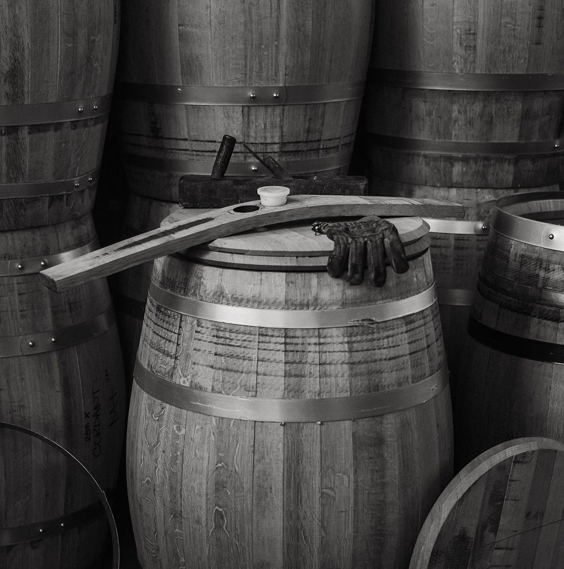 Wooden barrels with crossed tools and gloves on top in a rustic storage cellar