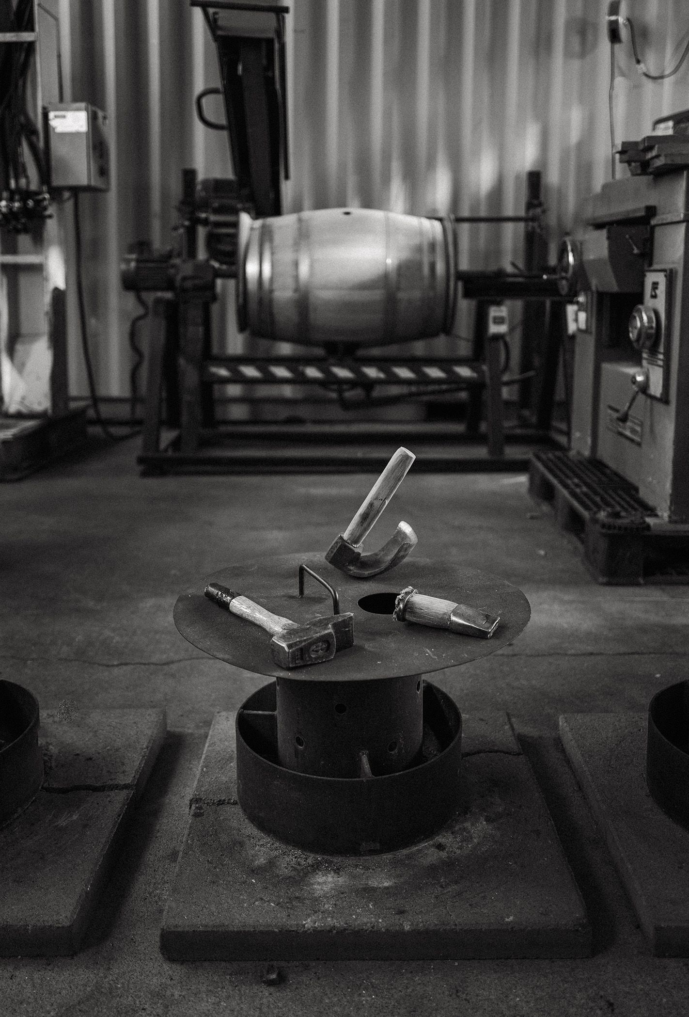 Industrial workshop with a metal cylinder on a machine and scattered tools on the floor
