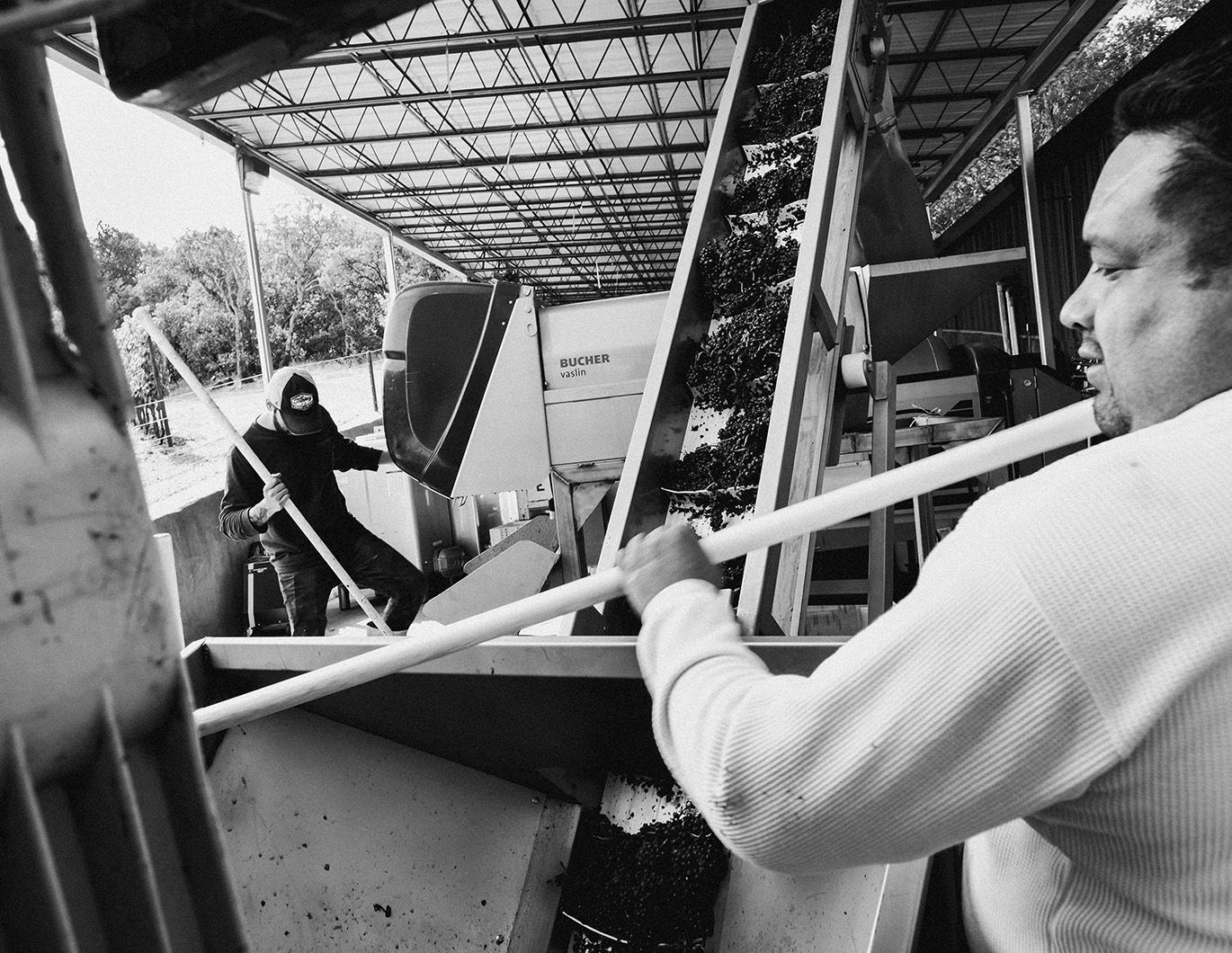 Workers using long tools to move materials in an industrial shed