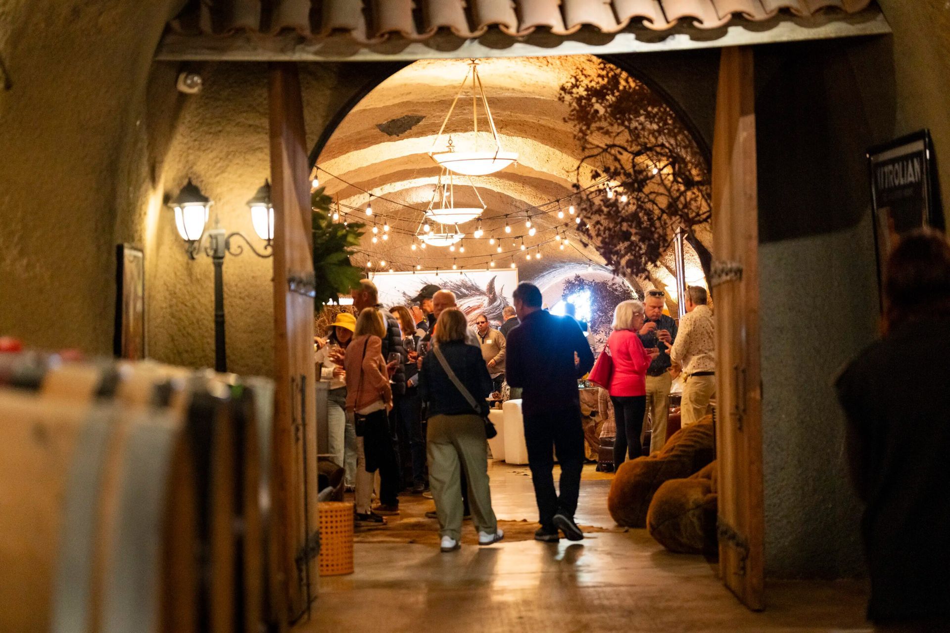 Crowded indoor market hallway with people walking under warm arch lights