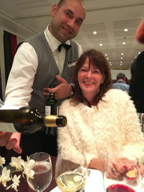 Man pouring wine beside a smiling woman at a restaurant table