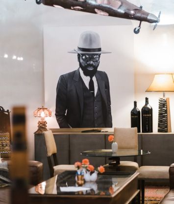 Restaurant wall with a black-and-white portrait above a booth, table, and warm lamp lighting