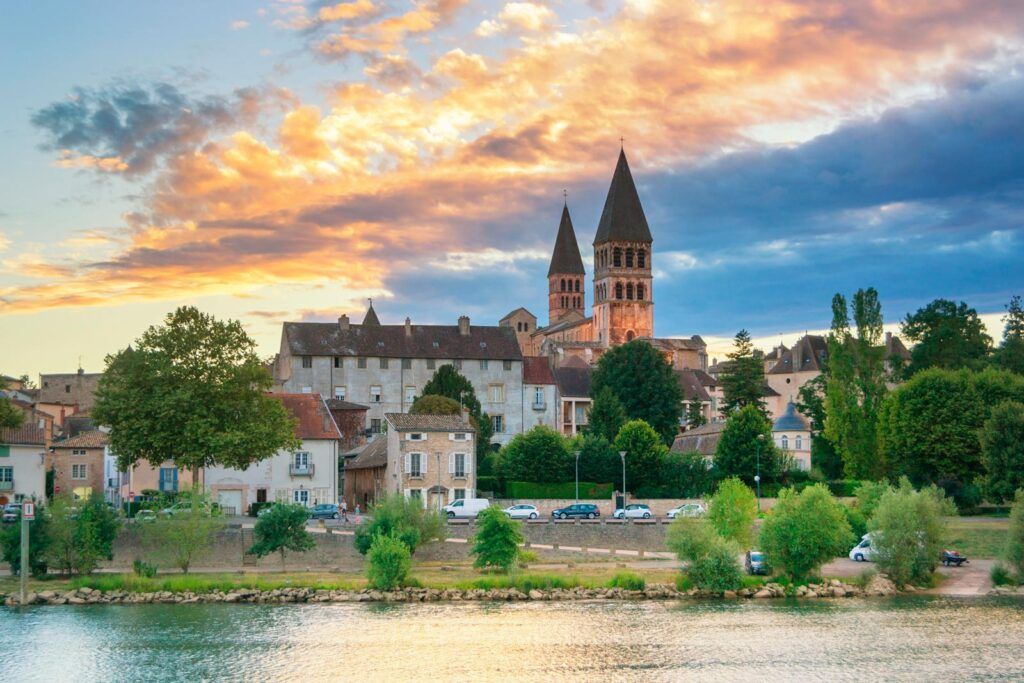 Riverfront town with a cathedral at sunset under a colorful sky