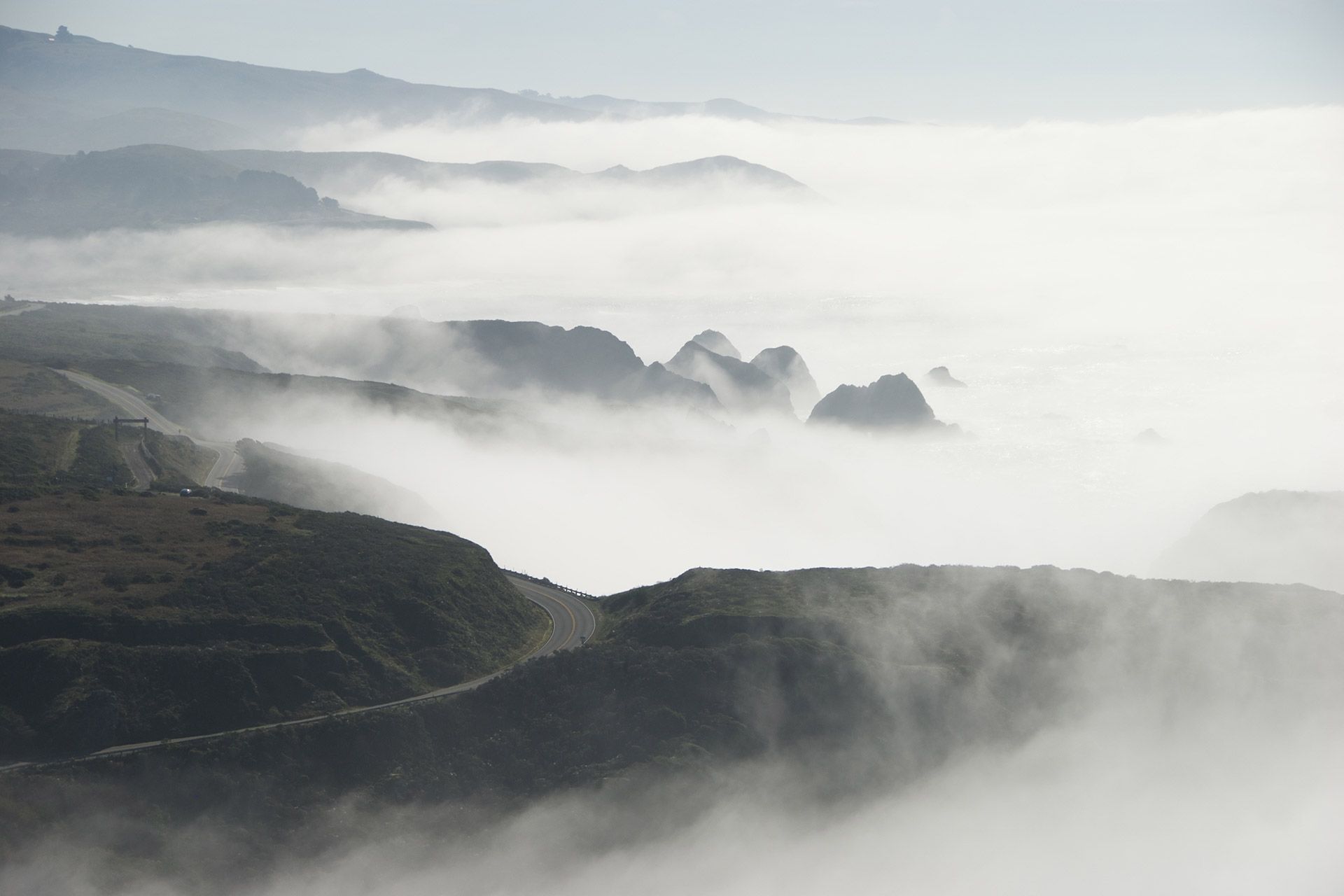 Fog rolling over dark mountain ridges at sunrise