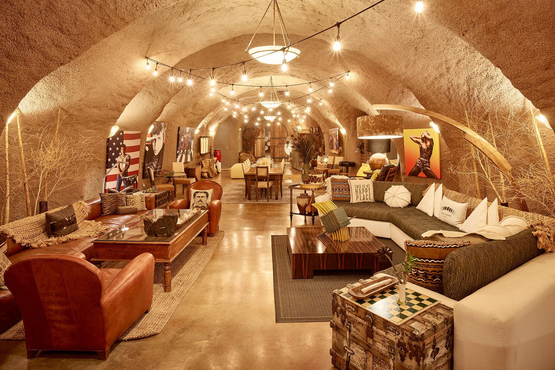 Cozy stone-walled lounge with sofas, rugs, lamps, and warm ambient lighting