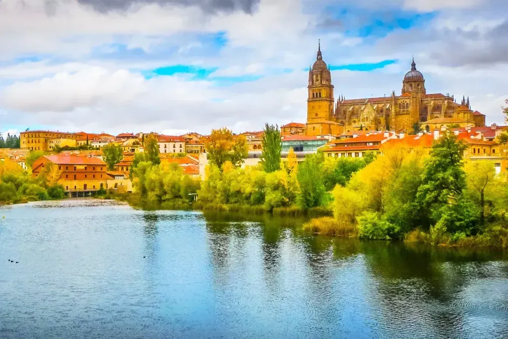 River with city skyline and cathedral towers under a bright blue sky in autumn colors
