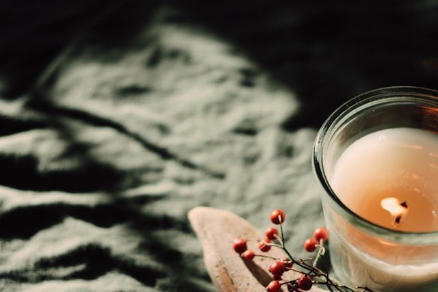 Lit candle in glass holder with decorative berries, symbolizing remembrance, cremation services Petaluma, CA
