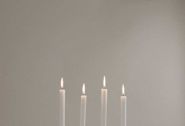 Four lit candles against neutral background, symbolizing remembrance, cremation services Santa Rosa, CA