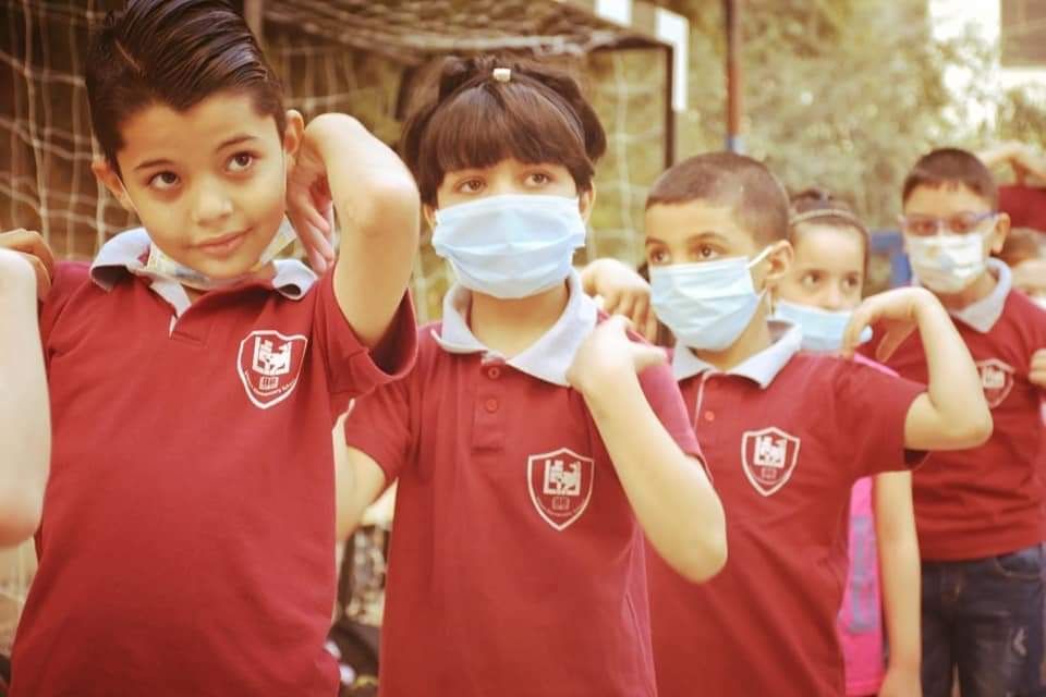 A group of children wearing face masks are standing in a line.