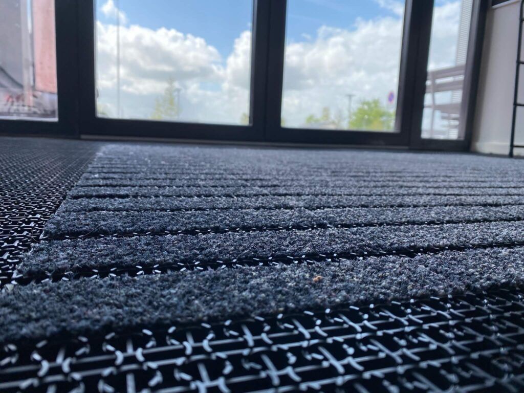 A close up of a door mat in front of a window