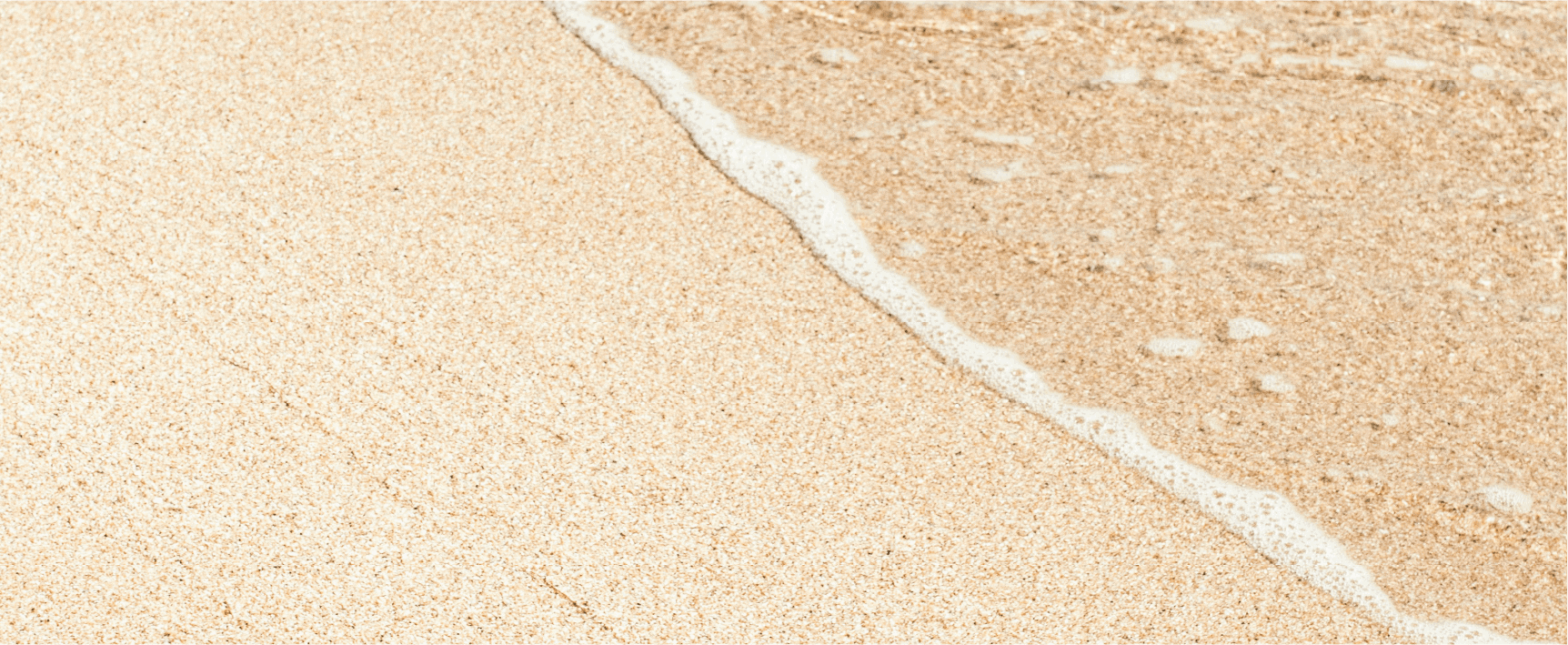 A close up of a sandy beach with waves coming in